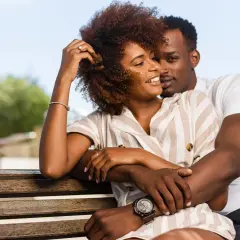 Un couple s'enlacent tendrement sur un banc, un moment de complicité qui évoque la prière des époux pour leur mariage.