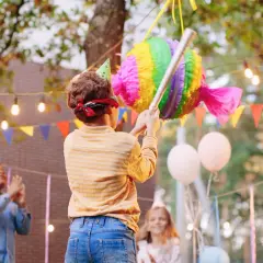 Enfants en fête, un garçon bandeau sur les yeux s'apprête à frapper une pinata colorée. L'art de fabriquer une pinata pour un joyeux anniversaire.
