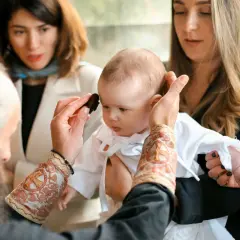 Cérémonie religieuse : un bébé est tenu par sa marraine. Le prêtre applique une onction. Peut-on changer de marraine ?