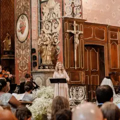 Une femme chante lors d'un mariage, accompagnée d'un orchestre. La prière universelle du mariage résonne dans l'église ornée.