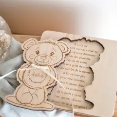 Ours en bois gravé avec le prénom Arthur, à côté d'une sphère en verre remplie de fleurs séchées.