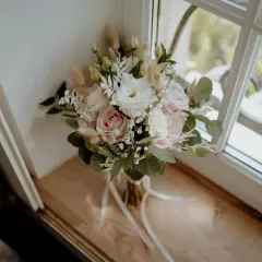 Un bouquet de mariage pastel avec des roses, des lisianthus et des herbes de la pampa. Une belle inspiration pour votre liste des fleurs pour mariage.