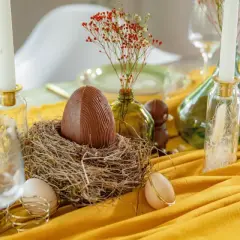 Un grand œuf en chocolat dans un nid, entouré d'œufs et de bougies, pour un joyeux dimanche de Pâques.