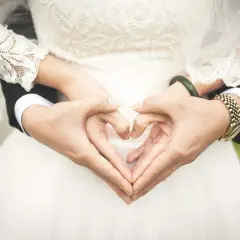 Les mains du jeune marié et de sa mariée forment un cœur sur la robe de mariée.