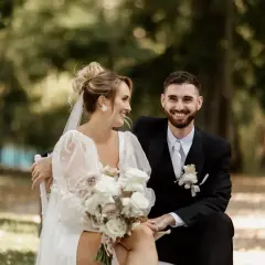 Un couple rayonnant, le marié en costume noir, la mariée en robe blanche, échangeant des regards complices lors de leur échange de voeux mariage.
