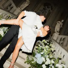 Un couple s'embrasse passionnément sur un escalier orné de fleurs, célébrant leur jour du mariage.