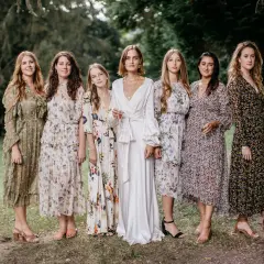 Six femmes en robes fleuries et une en blanc, probablement les témoins d'un mariage.