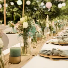 Décoration de chaise de mariage fait maison : table dressée avec des fleurs, des bougies et des serviettes en tissu nouées.