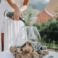 Un couple unit ses vies lors d'une cérémonie du sable, versant ensemble du sable de deux récipients dans un vase, symbolisant leur union.