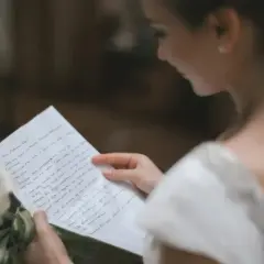 Une mariée lit une lettre d'intention mariage, un bouquet de callas à ses côtés.