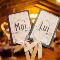 Deux pancartes "Moi" et "Lui" ornées de cœurs et d'oiseaux, parfaites pour le top des jeux de mariage.