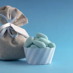 Un sachet de dragées bleues, parfait pour un thème baptême garçon, avec une petite coupelle rayée.