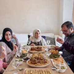 Un repas de famille pour l'Aïd el-Kebir : une grand-mère, des parents et des enfants partagent un festin copieux.