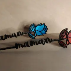 Deux roses décoratives avec le prénom "maman" gravé, l'une bleue, l'autre rouge.