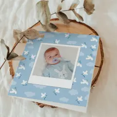 Carte de baptême originale pour un garçon, avec une photo de bébé sur fond bleu ciel orné de colombes et de nuages.