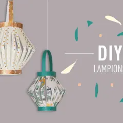 Trois lanternes en papier suspendues, décorées de motifs dorés et tropicaux.