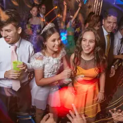 Des jeunes gens s'amusent lors d'une soirée bal, riant et dansant sous les lumières vives.