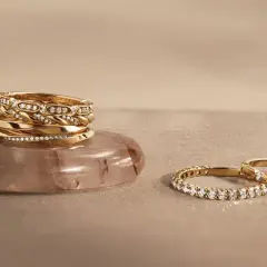Pile d'alliances en or et diamants sur une pierre, et deux autres bagues serties de diamants. Comment choisir son alliance ?