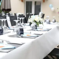 Table dressée pour une fête de baptême, avec des verres, des couverts et des décorations bleues.