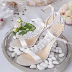 Escarpins blancs ornés de strass, entourés de dragées. Une question se pose : combien de dragées par personne pour un tel événement ?