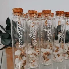 Bouteilles en verre avec fleurs séchées, bouchons en liège et breloques dorées. Parfait cadeau invité bapteme diy personnalisé avec des prénoms.