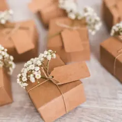 Petits pochons dragées à faire soi même, décorés de gypsophile et d'étiquettes kraft. Parfaits pour une touche personnalisée.