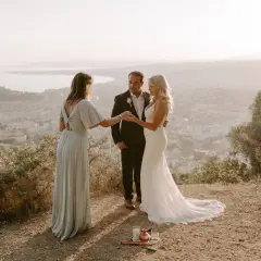Cérémonie d'elopement mariage intime au sommet d'une colline, avec vue sur une ville et la mer. Le couple échange ses vœux, officiés par une amie.