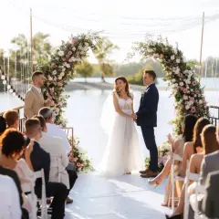 Cérémonie de mariage à la maison, un couple rayonnant sous une arche fleurie, entouré d'invités.