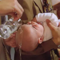 Un bébé est baptisé, l'eau bénite coule sur sa tête. Un moment solennel pour comprendre pourquoi baptiser son enfant.