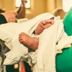 Les petits pieds d'un bébé enveloppé dans un linge blanc lors d'un baptême protestant.