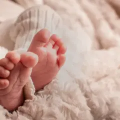 Petits pieds de bébé, tendrement enveloppés dans une couverture douce. Une image symbolisant la pureté et le début d'une nouvelle vie, peut-être en attente de la circoncision islam 7 jours.