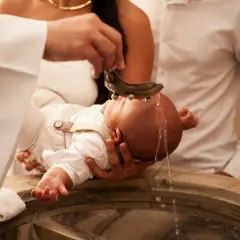 Cérémonie de baptême : un bébé reçoit de l'eau bénite sur la tête. Une famille est présente pour ce moment sacré.