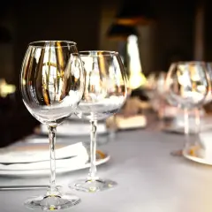 Trois verres à vin vides sur une table dressée, prêts pour un repas. Chaque verre reflète la lumière, comme un marque place verre.