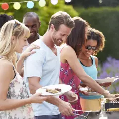 Des amis profitent d'un barbecue pour mariage en plein air, avec des brochettes et du maïs grillé.