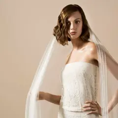 Une mariée porte une robe bustier en dentelle et un voile aérien, une création Delphine Manivet.
