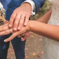 Mains jointes, alliances étincelantes, bouquet de mariée. Un moment clé parmi les plus belles demandes en mariage.