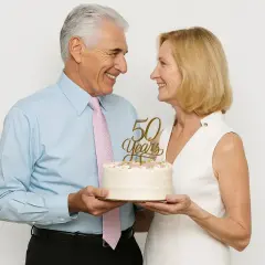 Un couple souriant célèbre son anniversaire de mariage avec un gâteau orné de "50 Years".