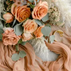 Un bouquet de roses corail et de pampas, drapé sur un tissu couleur pêche. Une touche de couleur de mariage parfaite pour une ambiance douce et romantique.