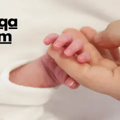 Main d'un nouveau-né tenant un doigt adulte. Le texte "Aqiqah Islam" est superposé, évoquant la tradition du mouton naissance islam.
