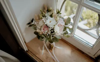 Un bouquet de mariage pastel avec des roses, des lisianthus et des herbes de la pampa. Une belle inspiration pour votre liste des fleurs pour mariage.
