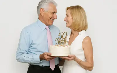 Un couple souriant célèbre son anniversaire de mariage avec un gâteau orné de "50 Years".