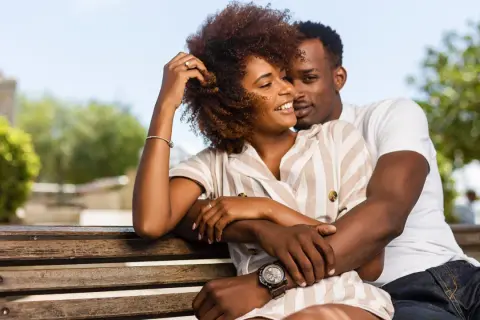 Un couple s'enlacent tendrement sur un banc, un moment de complicité qui évoque la prière des époux pour leur mariage.