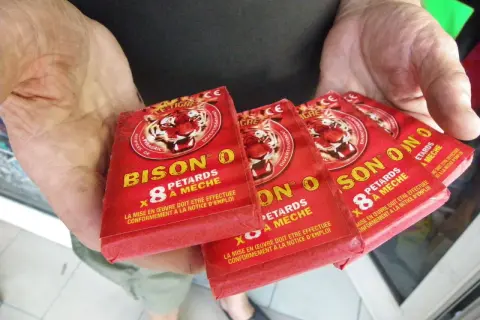 Des pétards "Bison O" sont tenus dans des mains. La question est : a-t-on le droit de faire péter des pétards ?