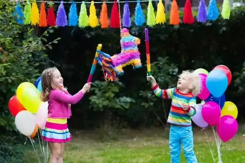 Des enfants joyeux s'amusent à casser une pinata colorée, une scène parfaite pour apprendre comment accrocher une pinata pour une fête.
