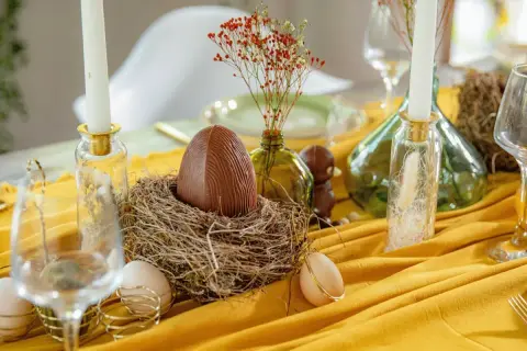 Un grand œuf en chocolat dans un nid, entouré d'œufs et de bougies, pour un joyeux dimanche de Pâques.