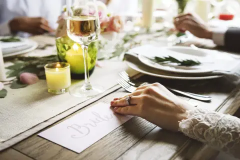 Un verre de champagne et une bougie illuminent une table dressée pour un mariage. La carte "Bride" annonce le cocktail de bienvenue.