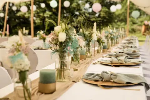 Décoration de chaise de mariage fait maison : table dressée avec des fleurs, des bougies et des serviettes en tissu nouées.