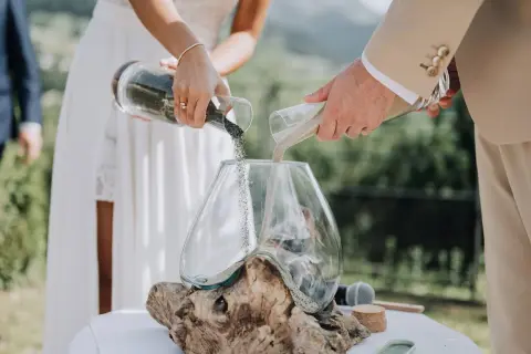 Un couple unit ses vies lors d'une cérémonie du sable, versant ensemble du sable de deux récipients dans un vase, symbolisant leur union.