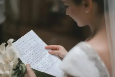 Une mariée lit une lettre d'intention mariage, un bouquet de callas à ses côtés.