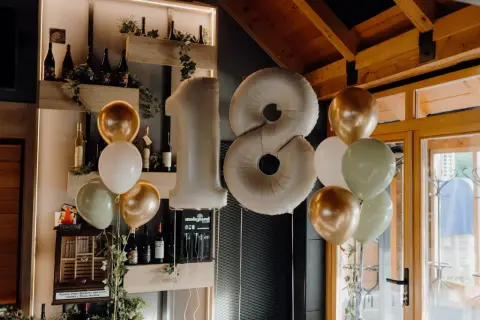 Ballons dorés, blancs et verts flottent près d'un grand ballon chiffre 18, parfait pour une fête d'anniversaire.
